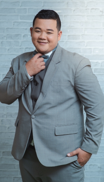 übergewichtiger Mann steht im Anzug vor einer Wand